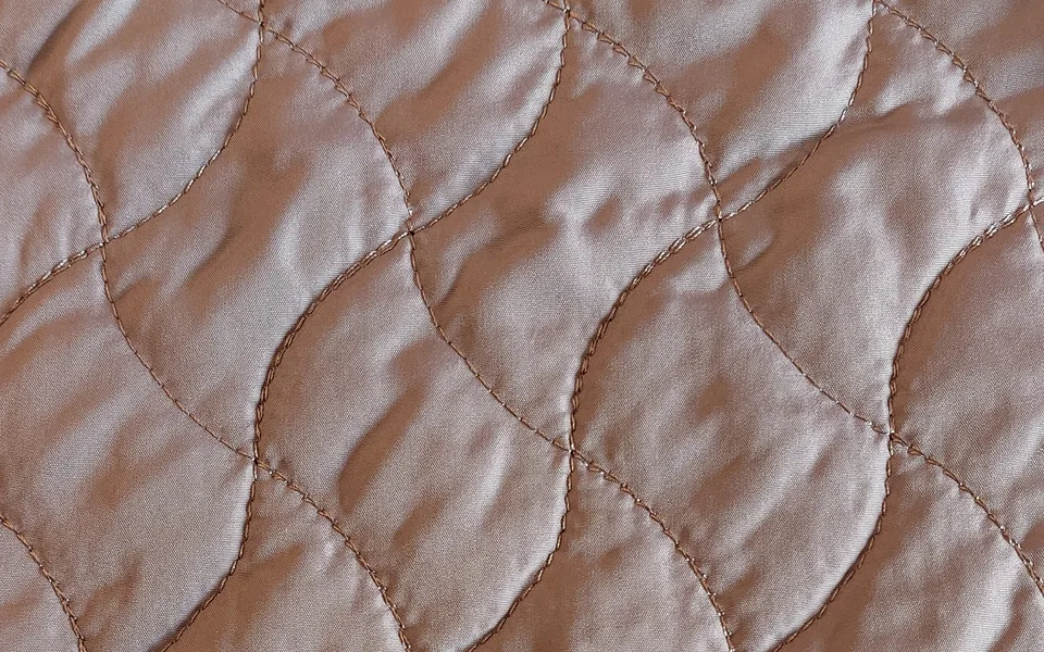 Light brown fabric with wavy diamond quilting stitches
