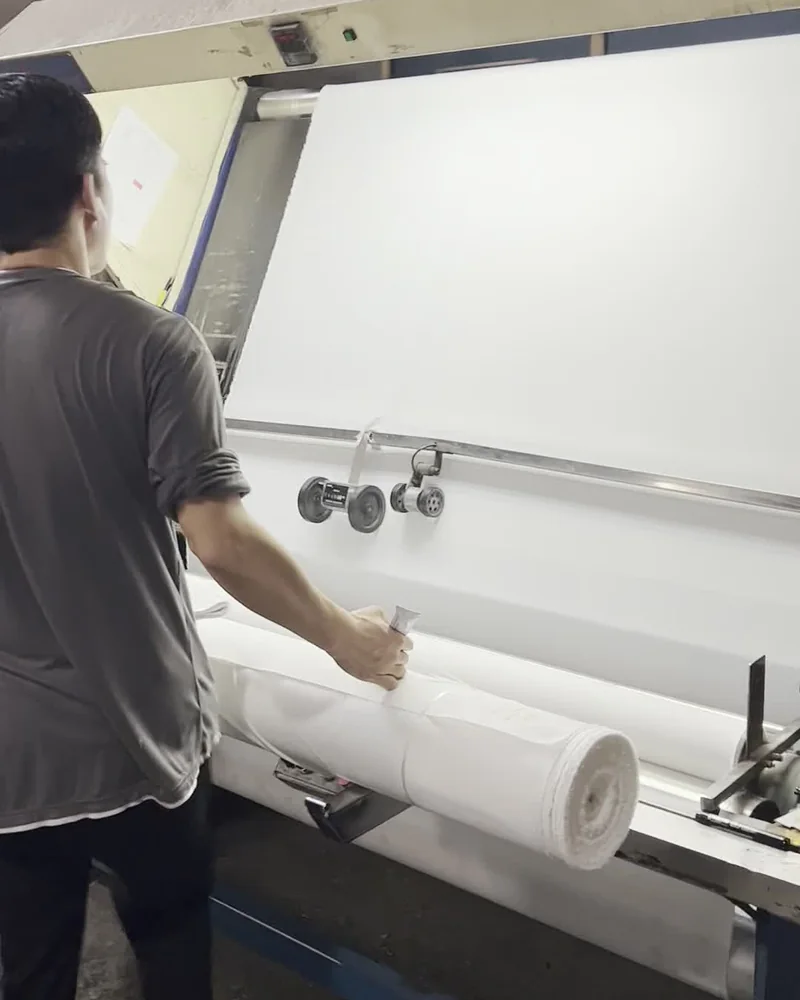 White fabric being reviewed at an illuminated inspection machine